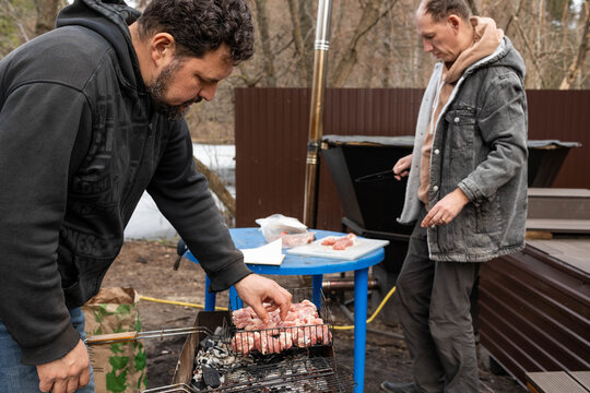 Friends are grilling meat outdoors.
