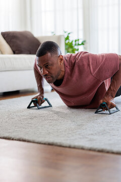 Man doing push-ups with handles in living room.