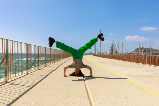 Woman Performs Handstand on Path Near Water 