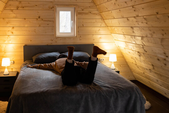 Person lies on bed in wooden room