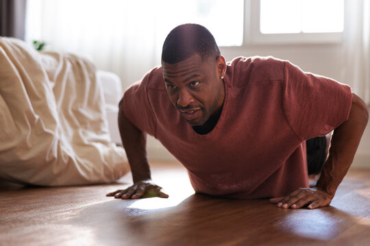Man doing push-ups on the floor in a bedroom.
