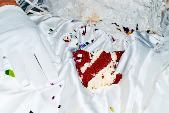 on the lap of a seated bride, cake rests on her stained white dress