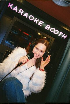 Young woman sings inside a karaoke booth at a fun entertainment