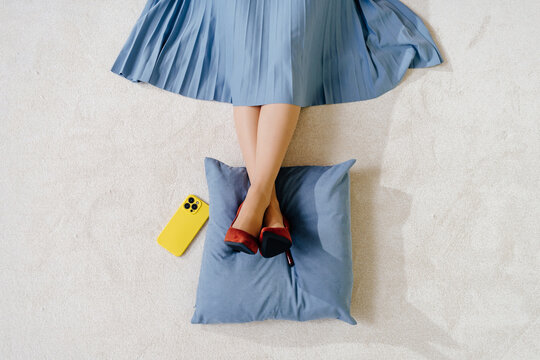 Top View of woman Resting Legs on Cushion with Smartphone Nearby