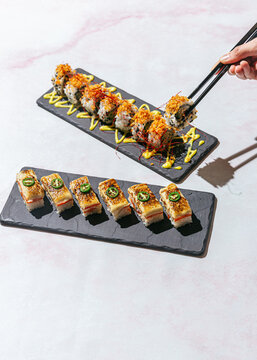 Vegan "salmon" aburi sushi with hand holding piece of sushi