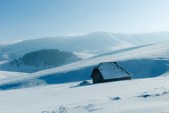 Snow covered cabin in mountain winter landscape