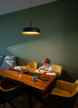 Child drawing alone at large dining table