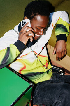 Man talking on phone sitting by green table