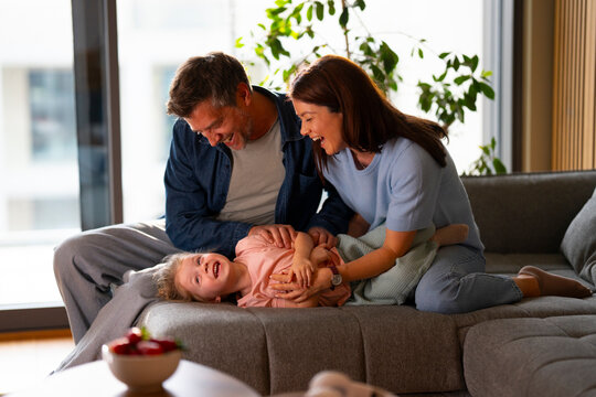 Parents playing with child on couch at home