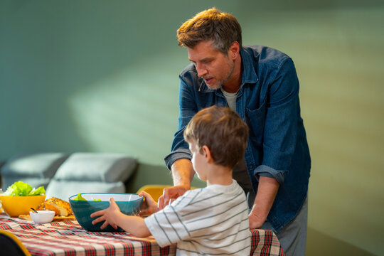 Father teaches son to prepare salad together