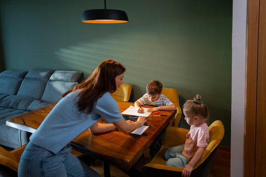 Mother helping children with drawing at table