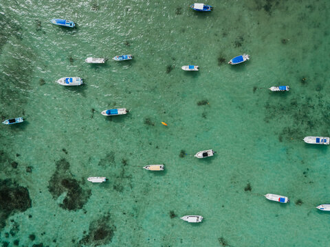 Aerial view of boats anchored in shallow turquoise lagoon
