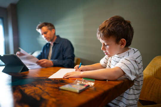 Child drawing while father works in background