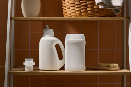White laundry detergent bottles and cleaning brush on a wooden shelf