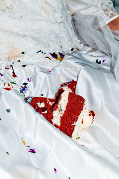 a cake portion resting on the lap of a bride over satin and tulle