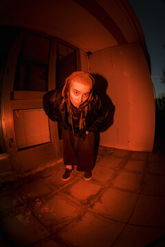 Person Bends Down in a Doorway During Night Time With Orange Light