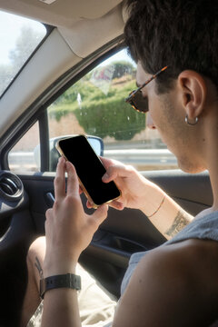 Young Man Using a Smartphone in a Car