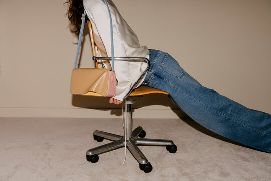 Fashion Handbag Draped Over Office Chair With Jeans