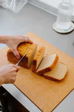 Woman's hands slicing a loaf of bread into slices