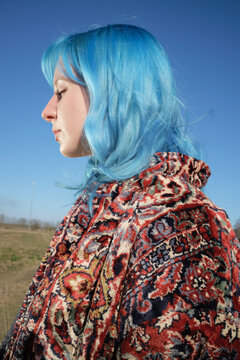 Young woman with blue hair in a field on a sunny day