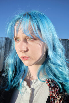 Young woman with blue hair standing outdoors in clear weather