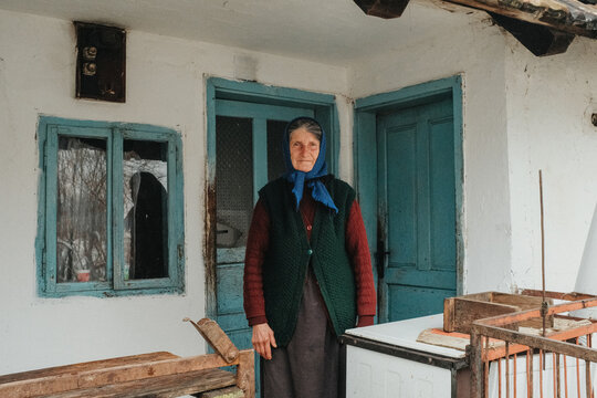 Elderly woman standing at old house doorway in winter