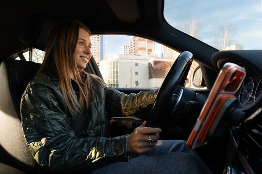Woman Smiling in Driver's Seat with Mounted Smartphone in City
