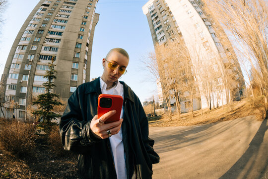 Young Person Checks Phone Near Tall Buildings in the City