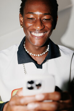 Man using smartphone indoors with pearl necklace