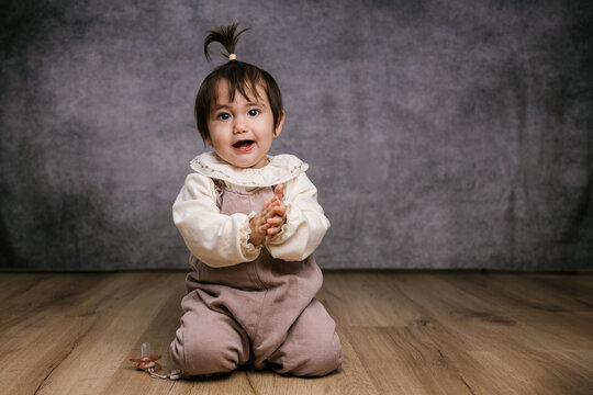 Happy baby girl clapping in a studio