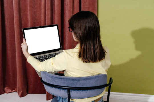 Woman Showing Blank Laptop Screen While Sitting on Chair Back View