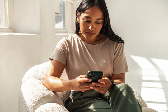 Brunette Woman Sitting in Armchair Using Phone
