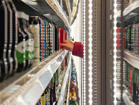 Customer Reaching for a Beverage Can in  Supermarket Cooler