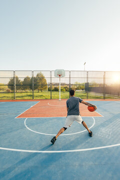 Man in outdoor basketball practice at sunset on court
