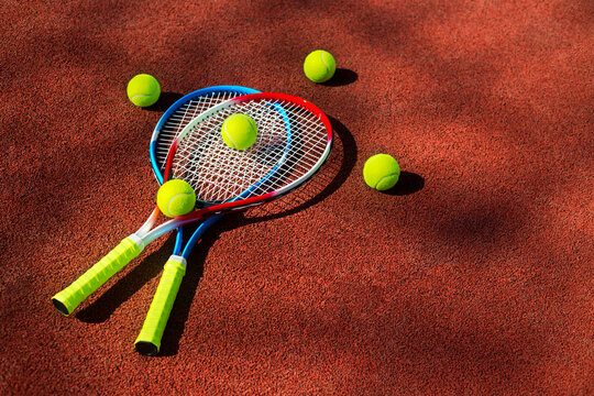 Two tennis rackets and five balls on a tennis court.