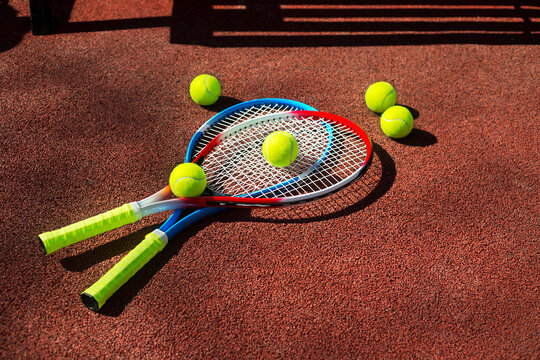 Two tennis rackets and five balls on a tennis court.