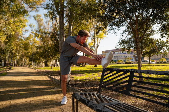 Man Stretching Leg Outdoors in Park