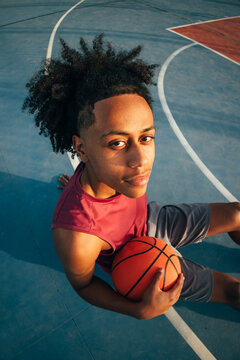 Young athlete sitting on outdoor basketball court