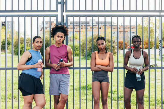 Athletes with water bottles standing by the fence