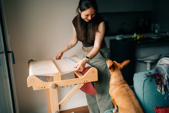 Woman Weaving Fabric While a Dog Watches in a Home Setting