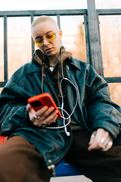 Young Person Listens to Music While Sitting at a Bus Stop