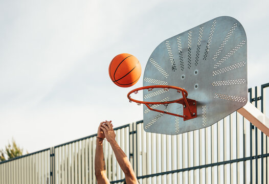 Player shooting basketball toward the hoop outdoors