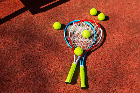 Two tennis rackets and five balls on a tennis court.