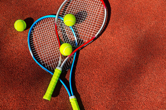 Two tennis rackets and three balls on a tennis court.
