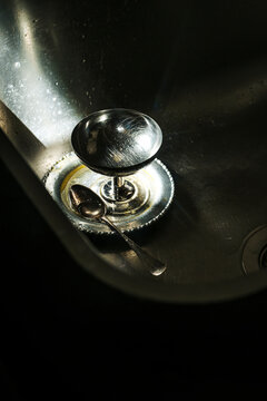 Metal Bowl and Spoon in a Kitchen Sink With Sunlight Reflecting