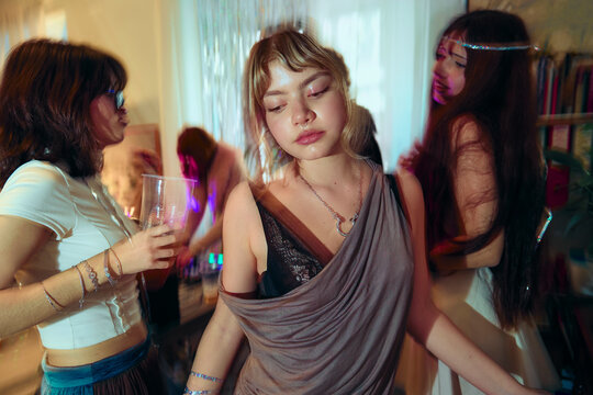 Woman dancing at house party holding drink indoors