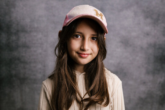 Young girl smiling wearing baseball cap looking at camera