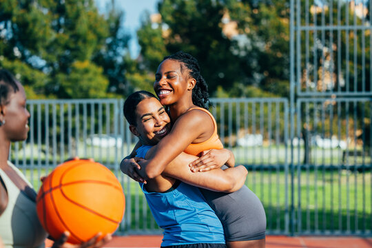 Friends embracing on outdoor basketball court