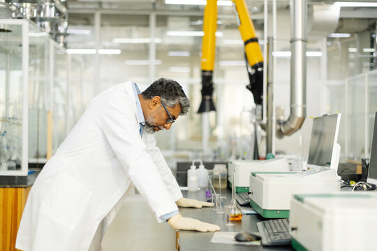  Tired Indian scientist in white coat working in laboratory