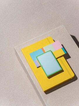 Bright yellow notebook and colorful sticky notes arranged on neutral